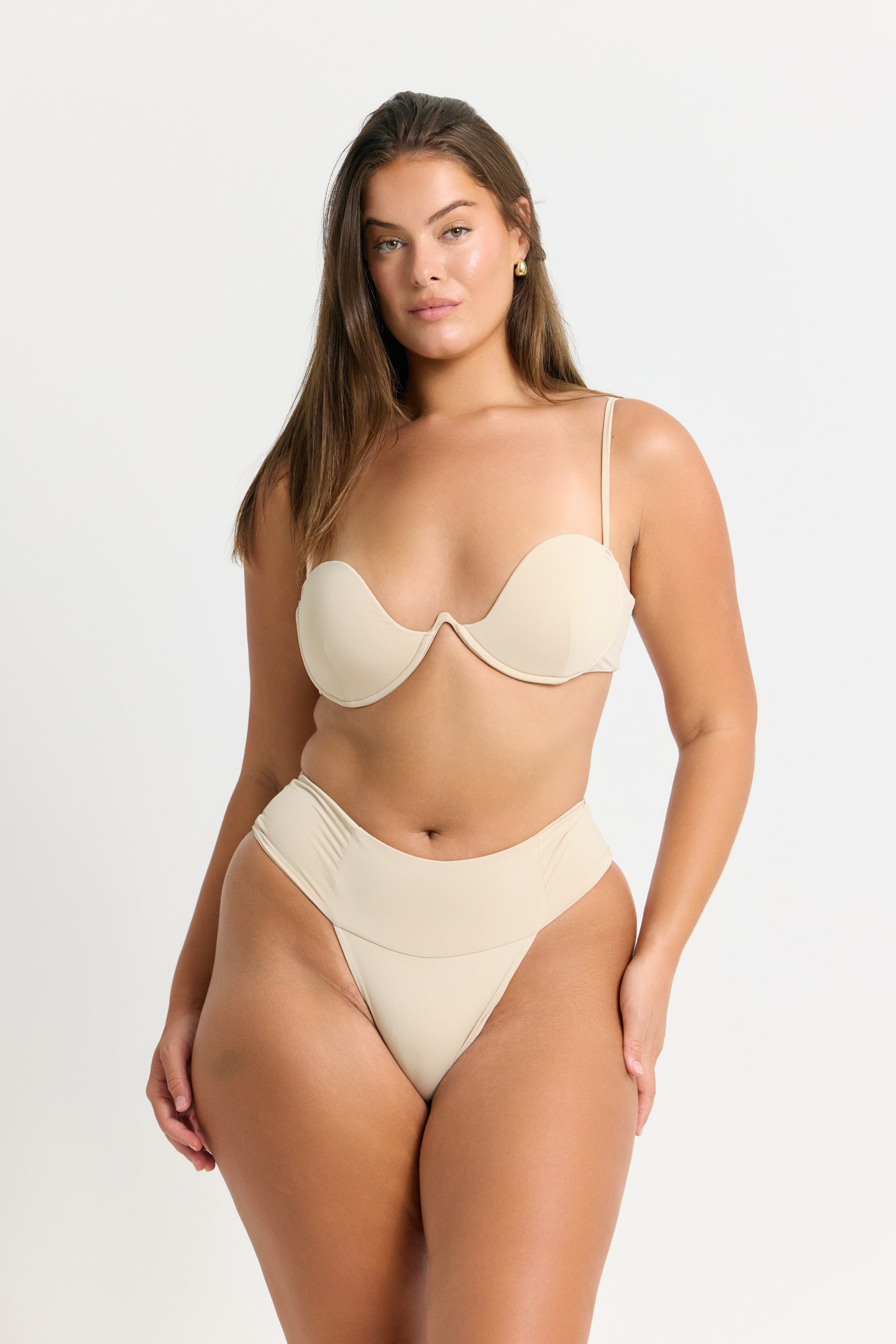 Woman wearing a coconut bikini bottom on a white background