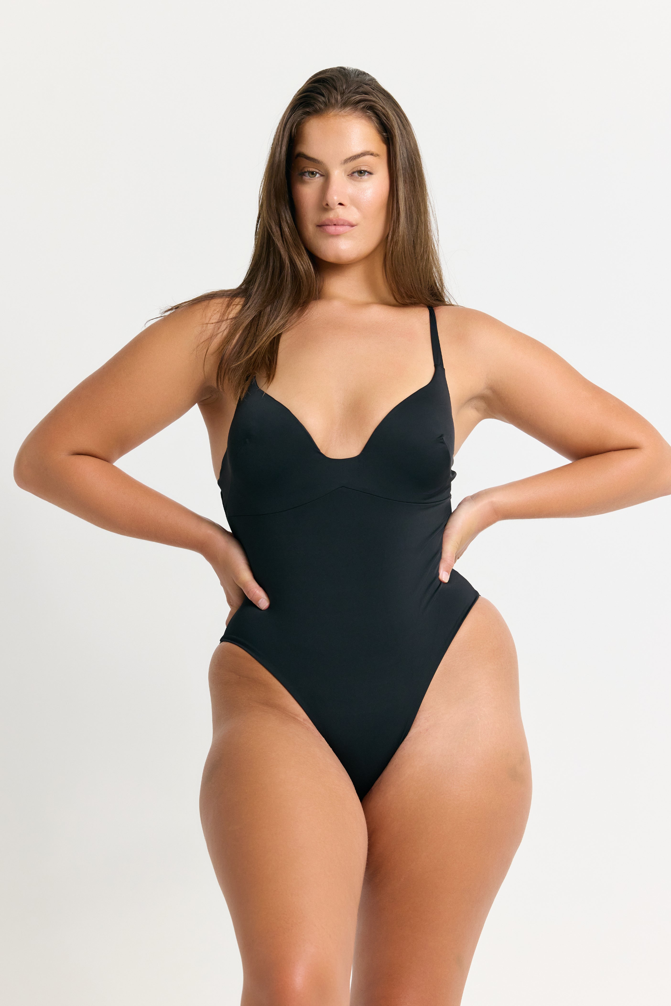 Woman wearing a black one piece swimsuit on a white background