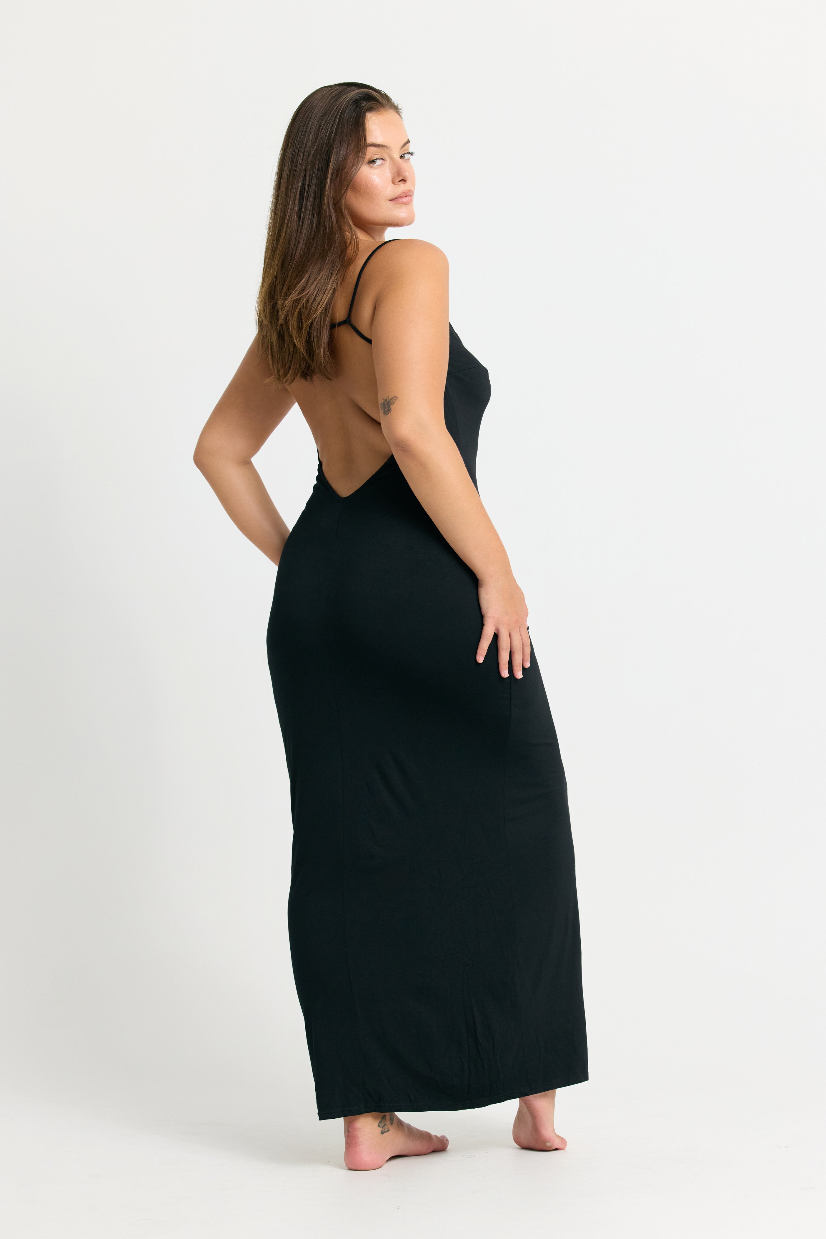 Woman wearing a black maxi dress with an open back on a white background