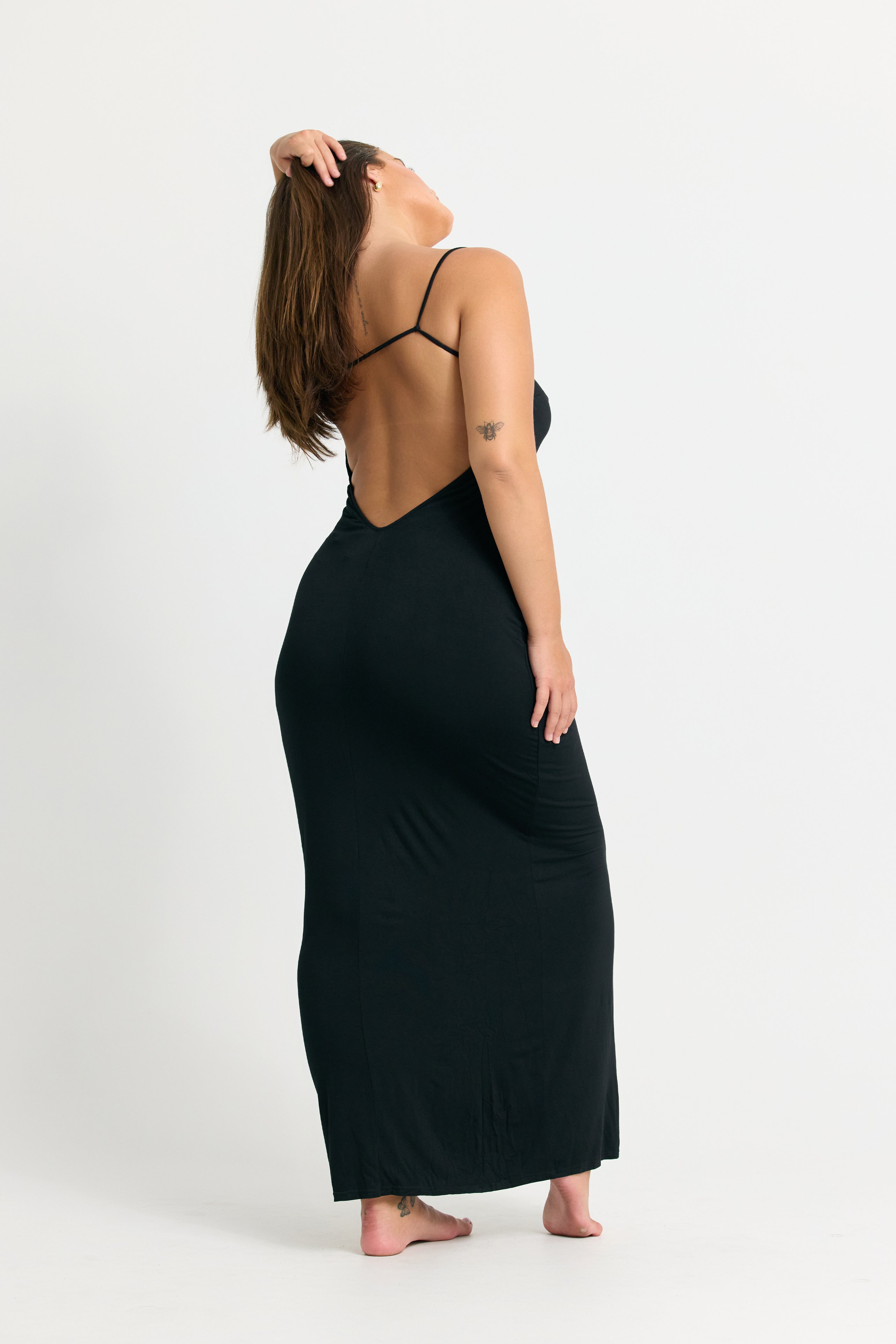 Woman wearing a black dress with thin straps on a white background