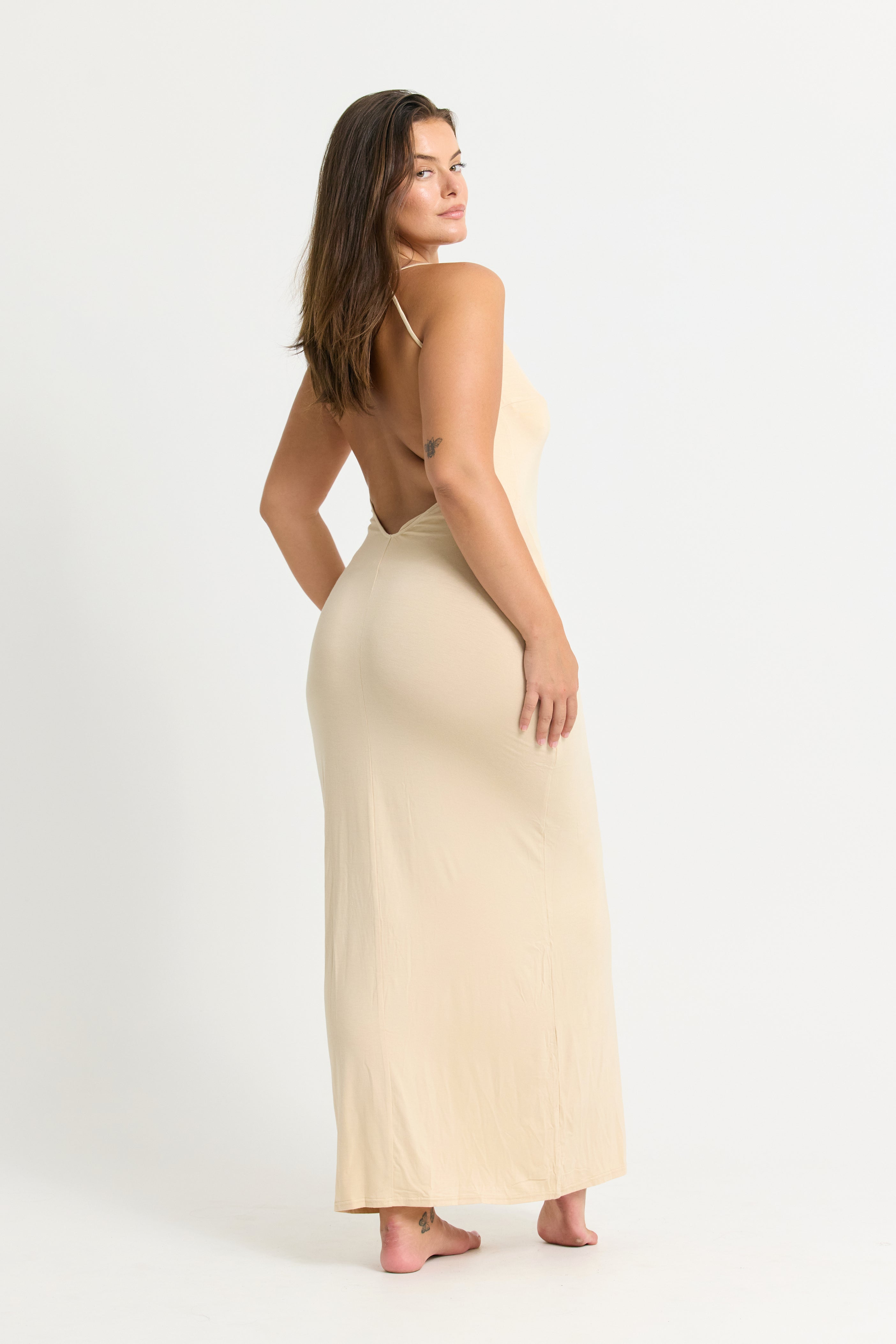 Woman wearing a beige maxi dress with spaghetti straps on a white background 