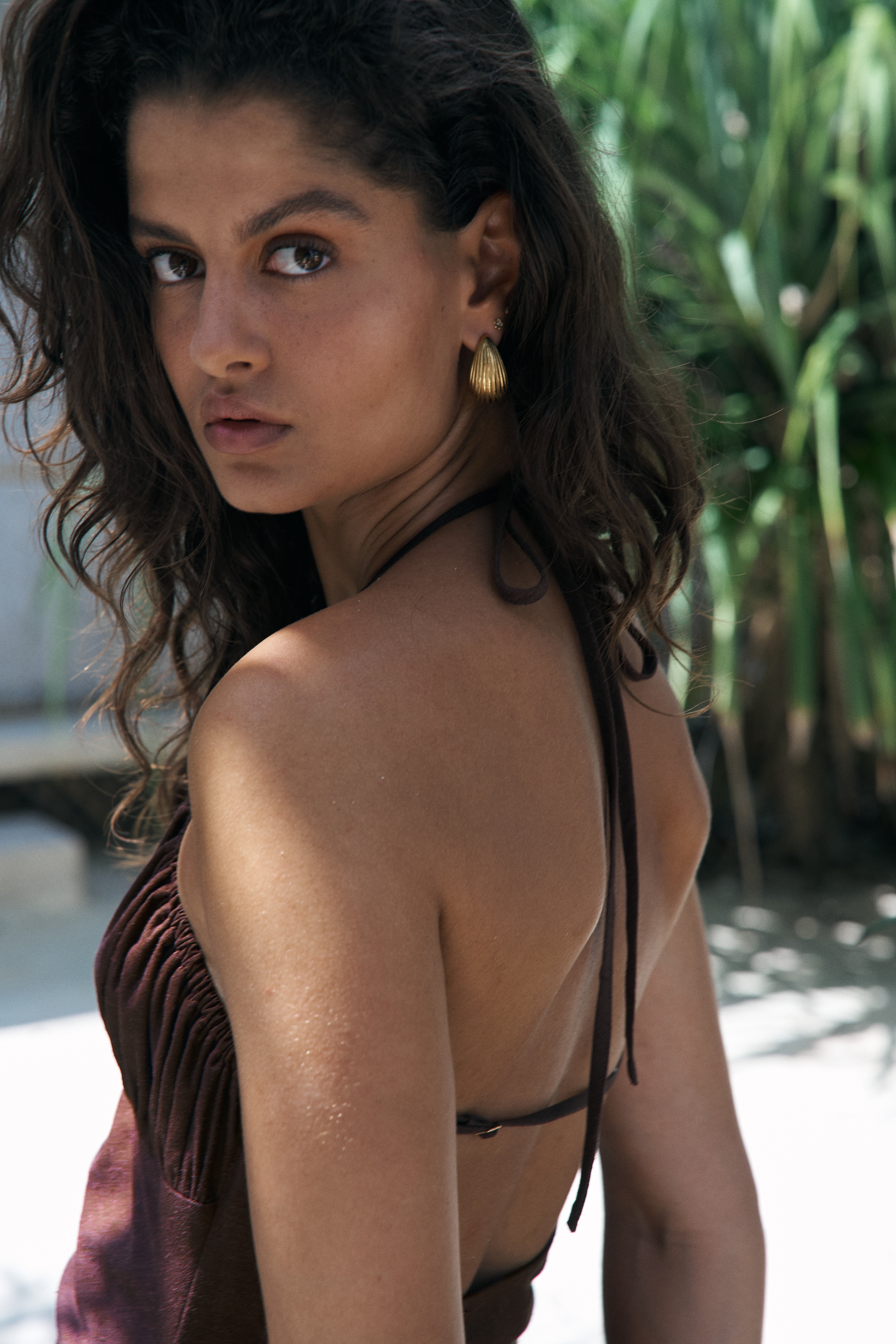 Woman wearing a brown fringe top with a blurred natural background