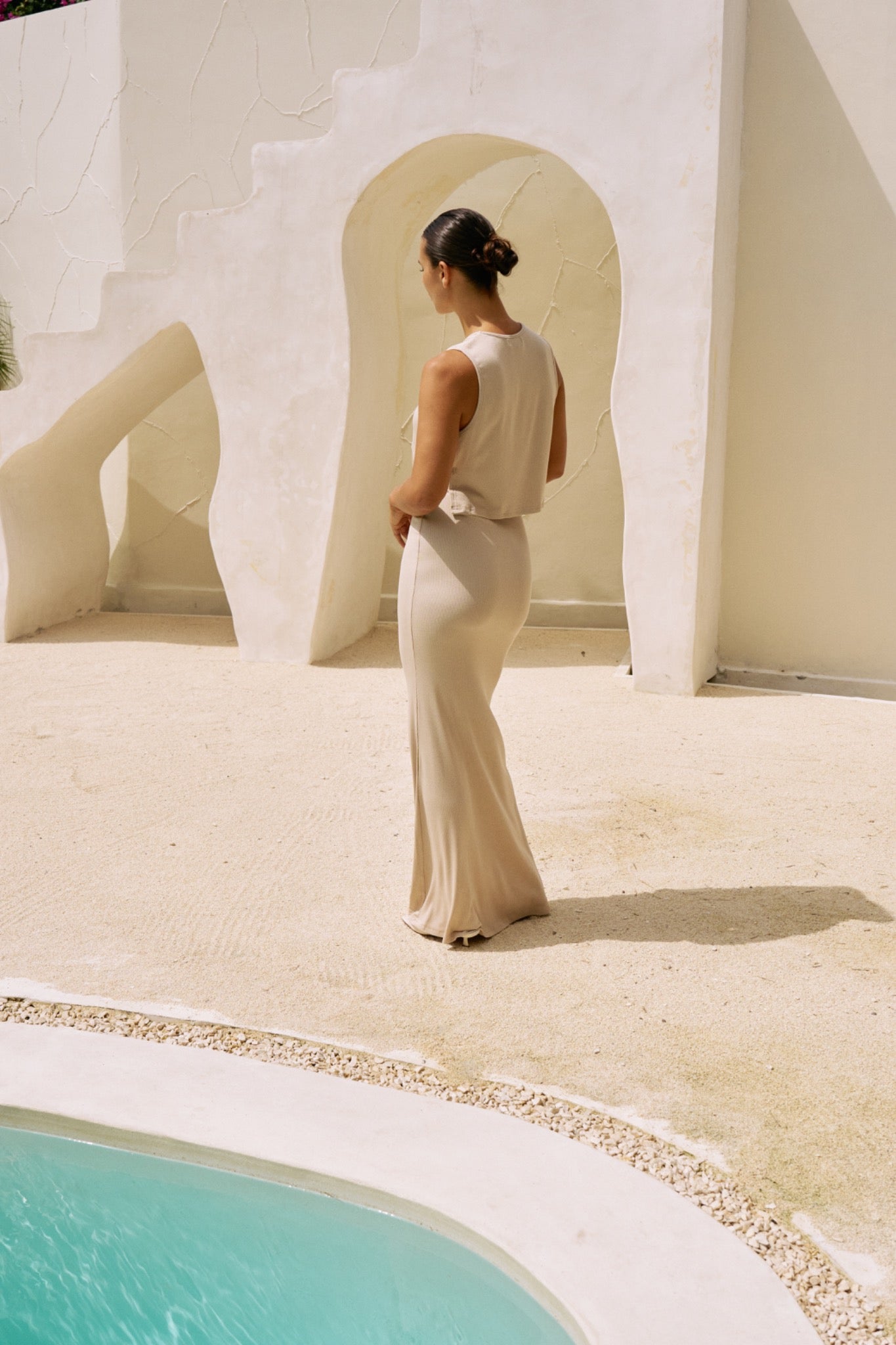 Back view of the Simi Top and Dom Maxi Skirt in Coconut near a poolside setting.