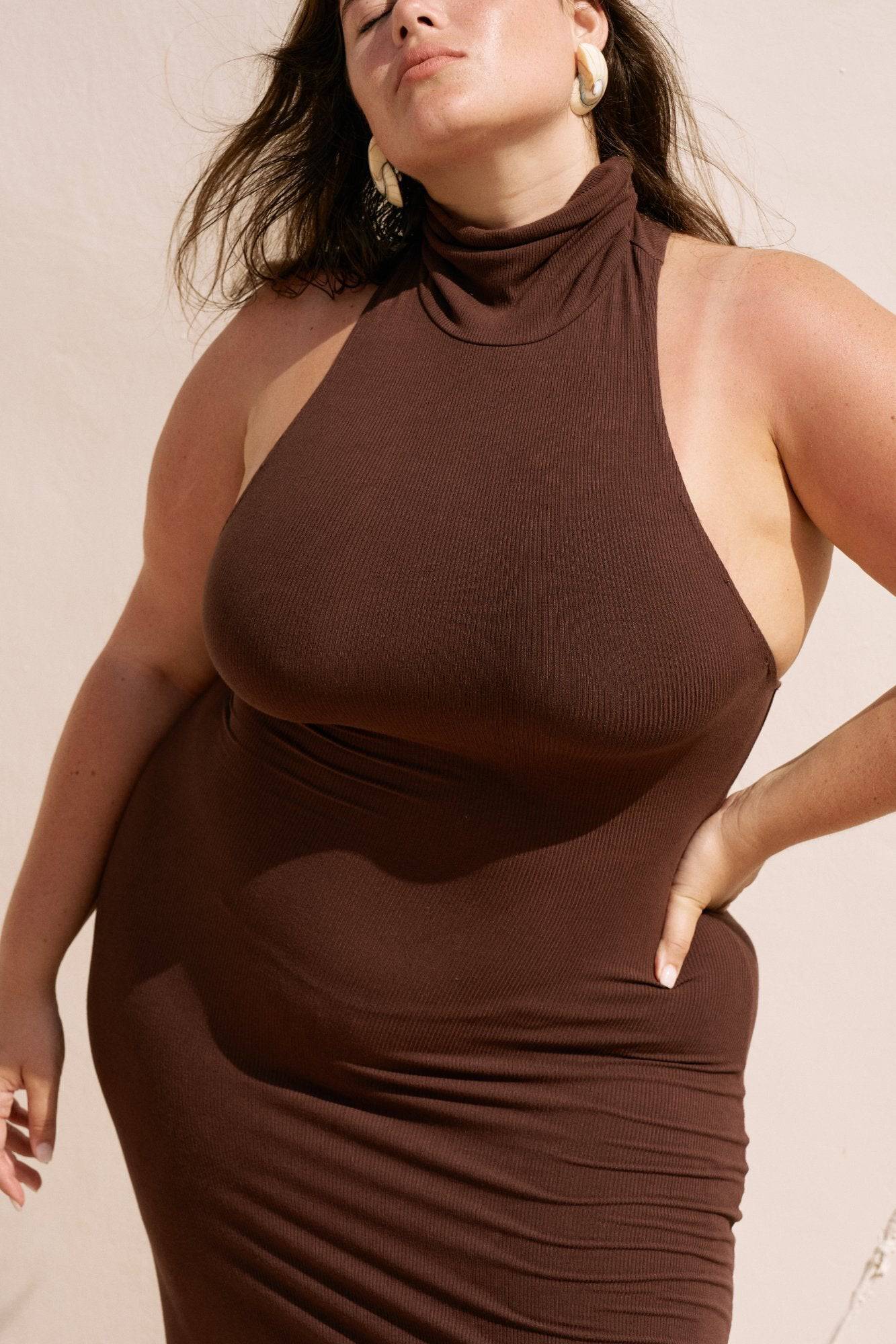 Riot Lounge Maeve Maxi Dress in chocolate color, flowing fabric, and elegant design, displayed on a hanger.