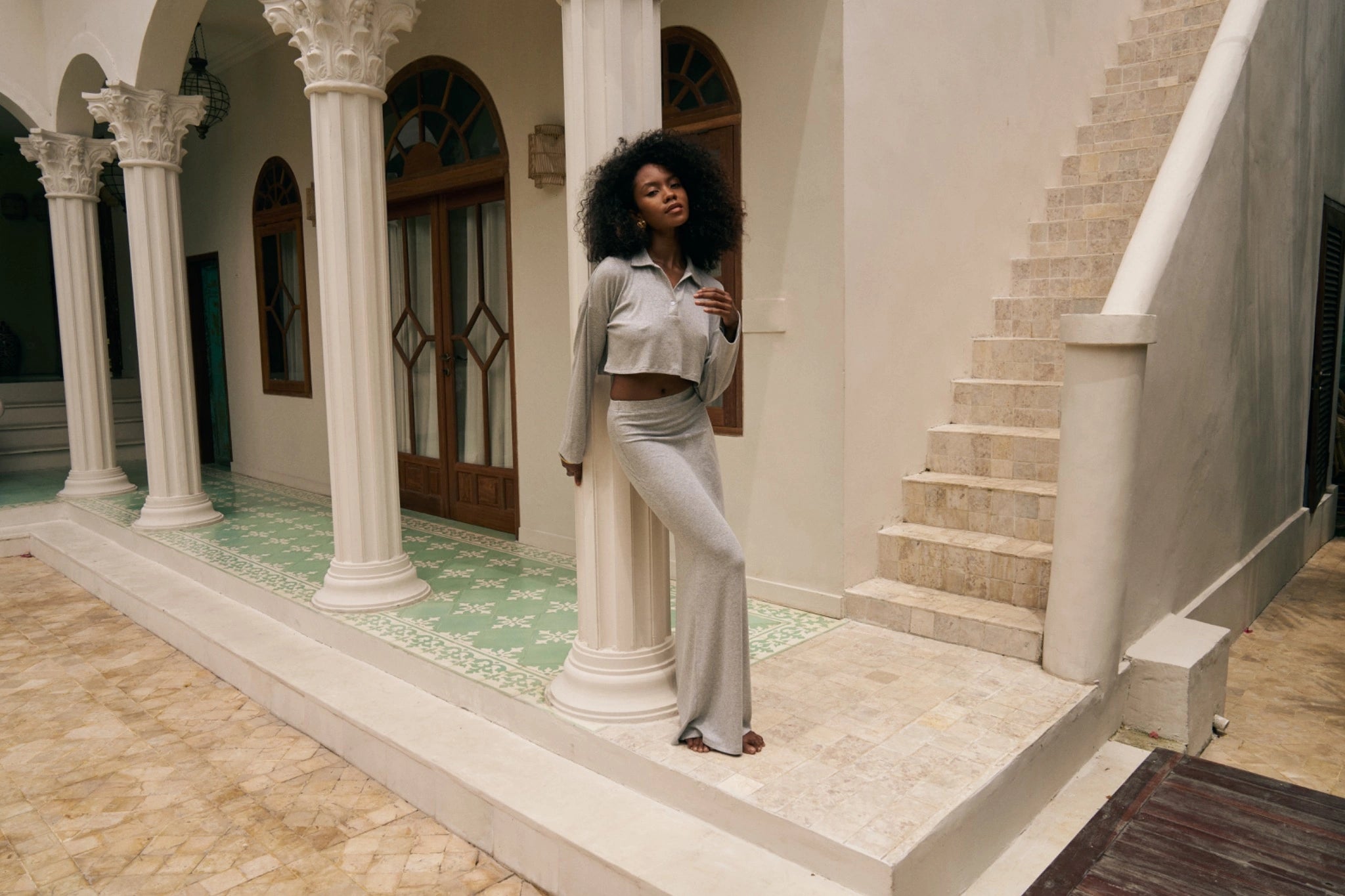 Woman wearing long sleeved top and maxi skirt standing in a decorative outdoor setting with columns and steps.