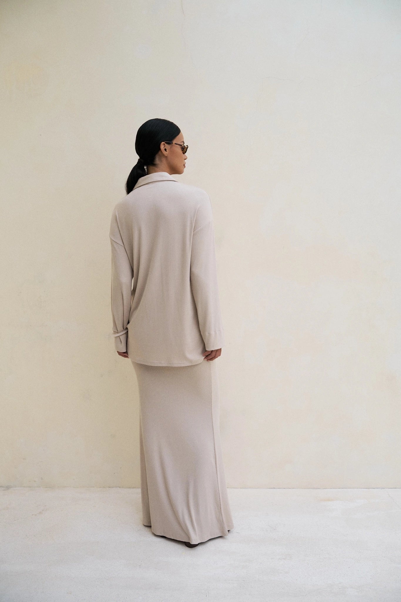woman wearing a coconut/beige top and maxi skirt against a plain white background