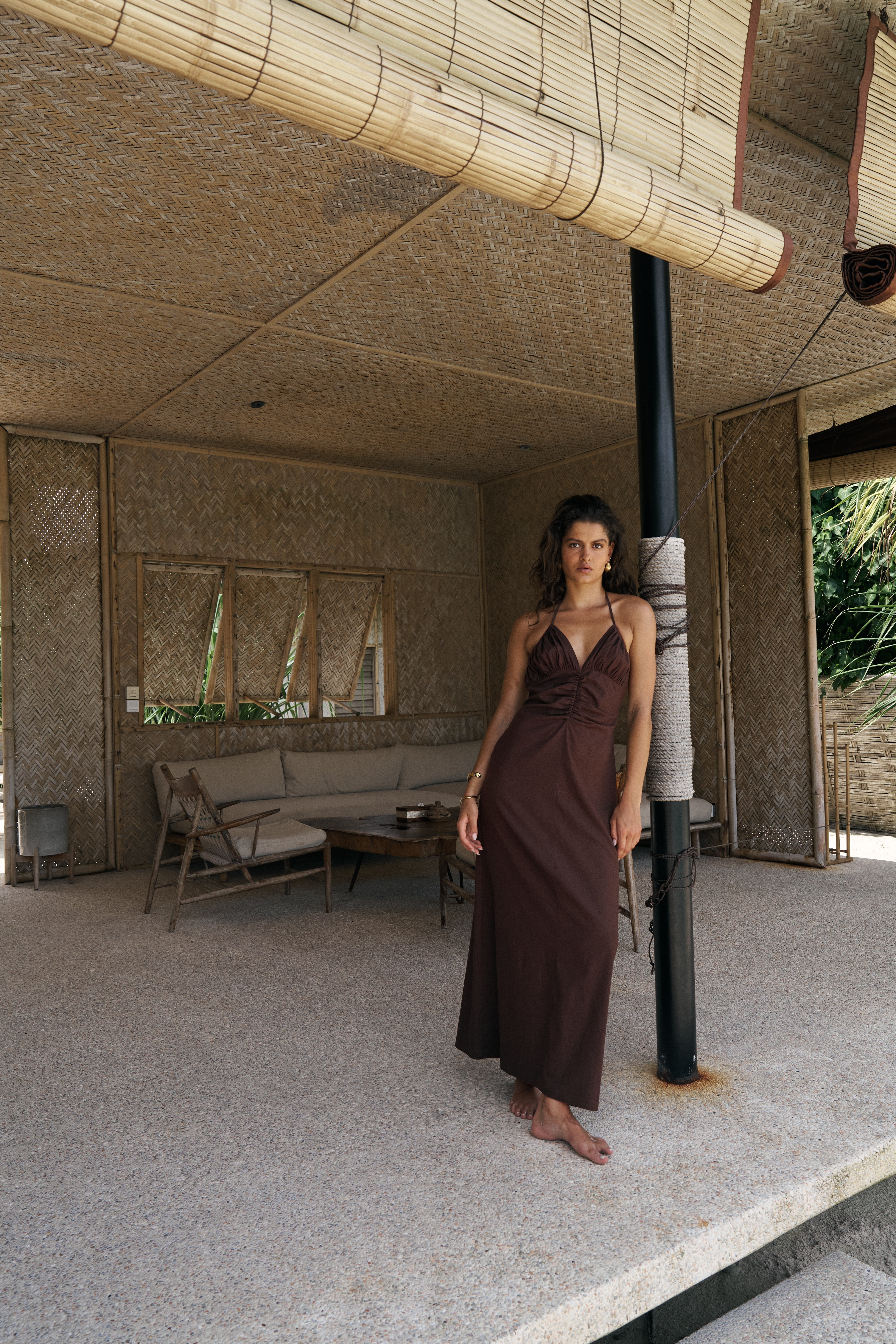 Woman in a brown dress standing in a modern indoor setting with neutral tones.