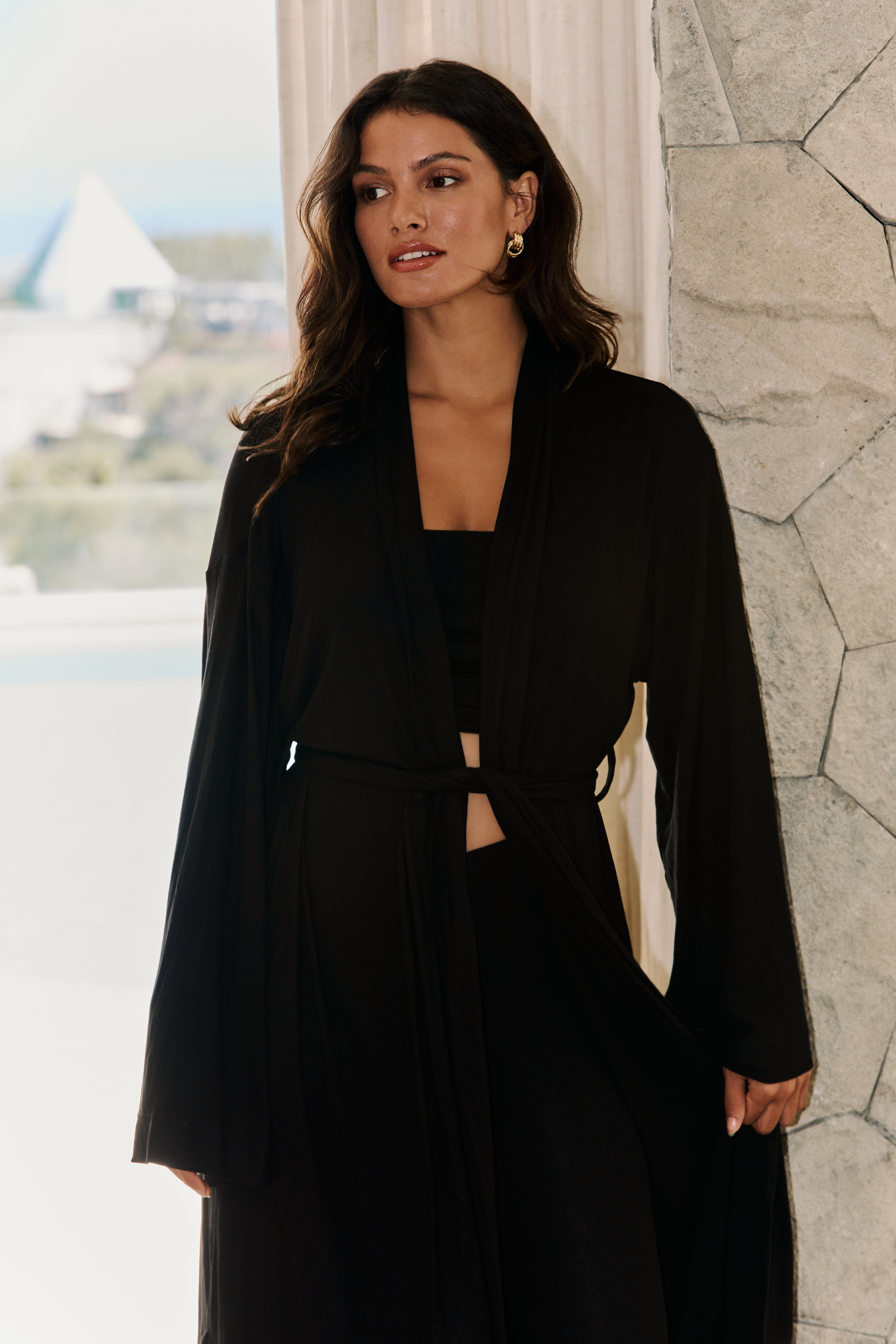 Close-up of black Riot Lina kimono/robe layered over black bandeau top with waist tie detail.