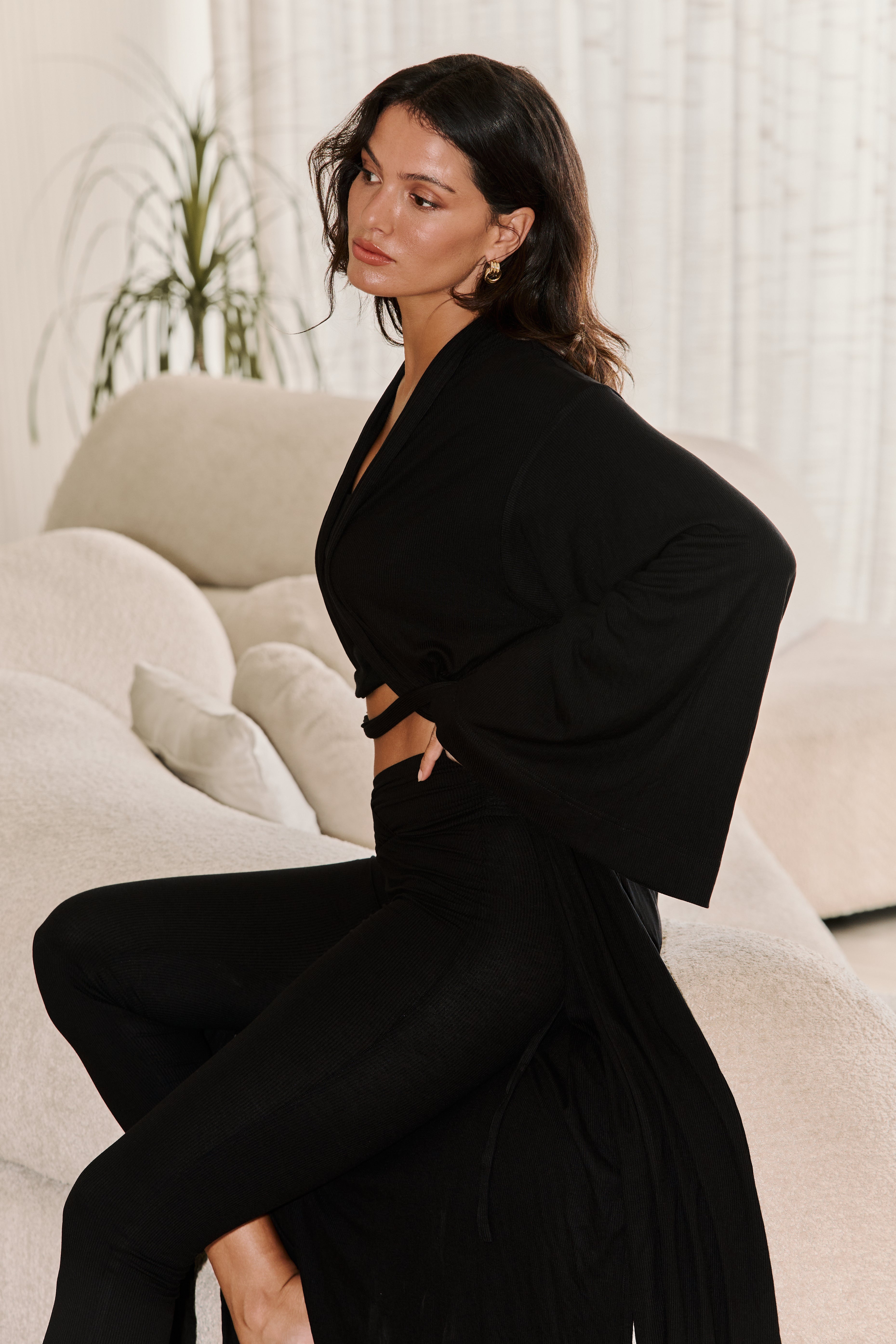 Side view of black knit kimono/robe  with wide sleeves styled over black leggings and bandeau top.