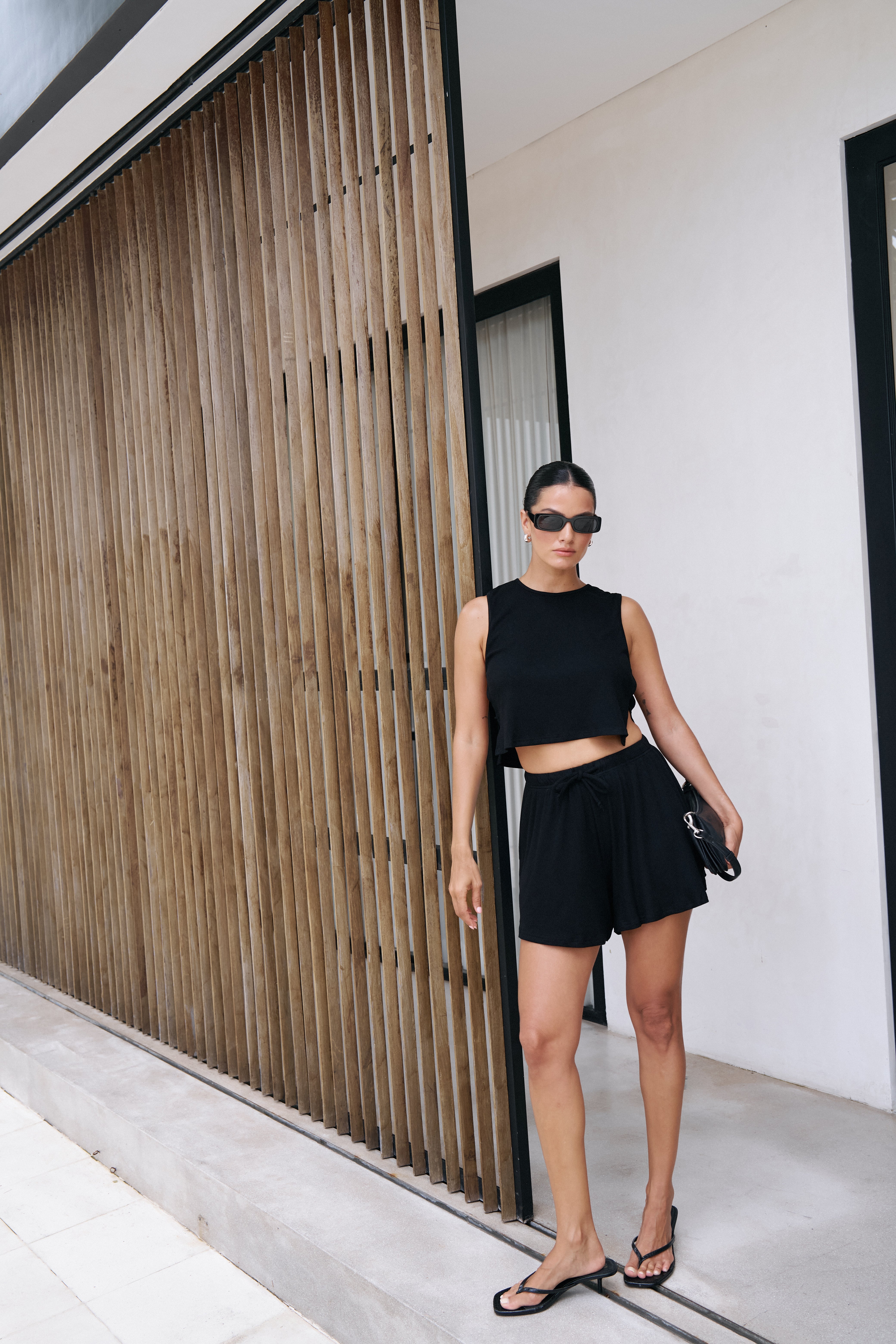 Riot Lounge Simi Side Strap Tank top in jet black, featuring slim straps and a fitted design, displayed on a plain background.