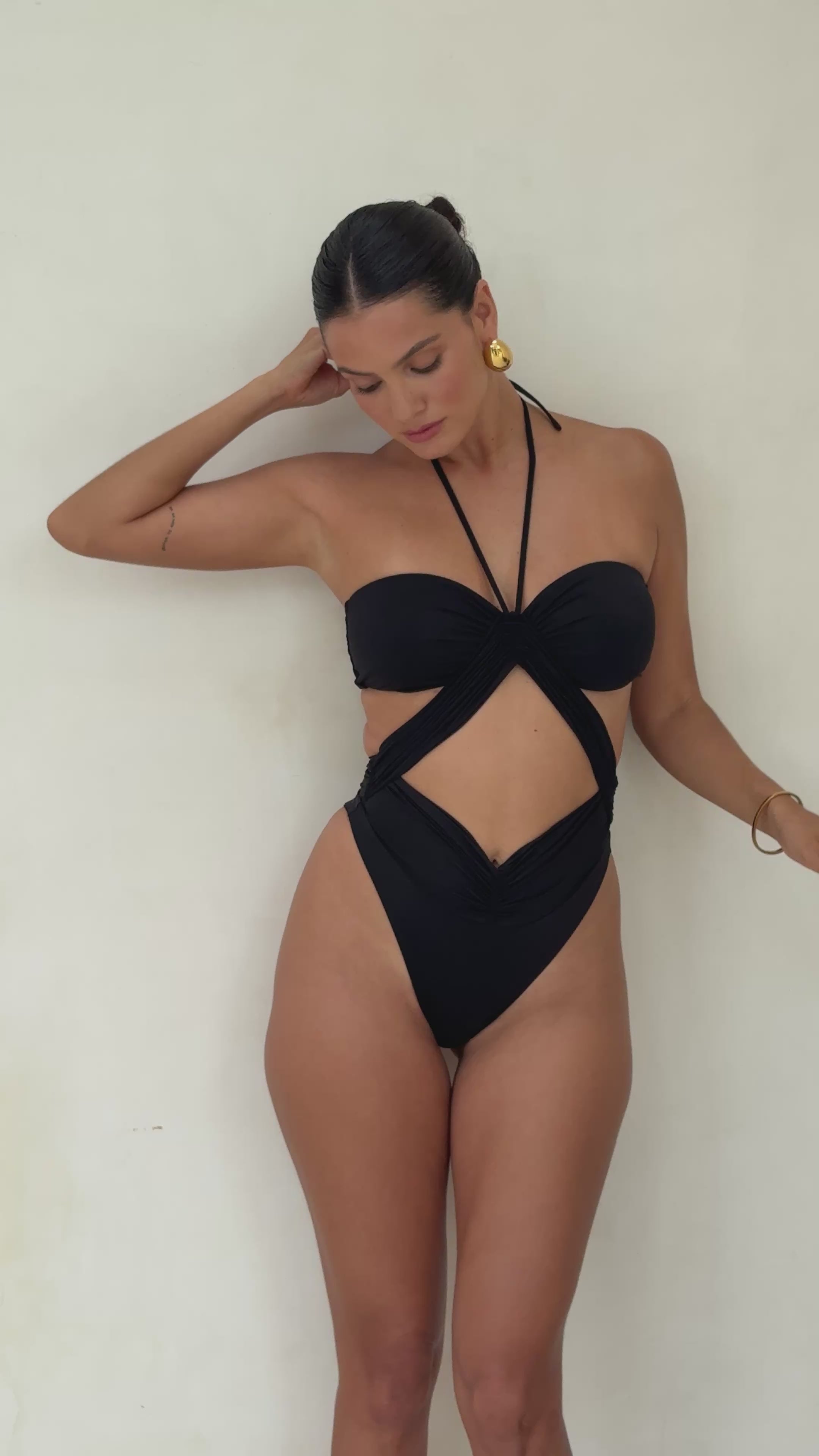 Model in a black Riot one piece swimsuit.