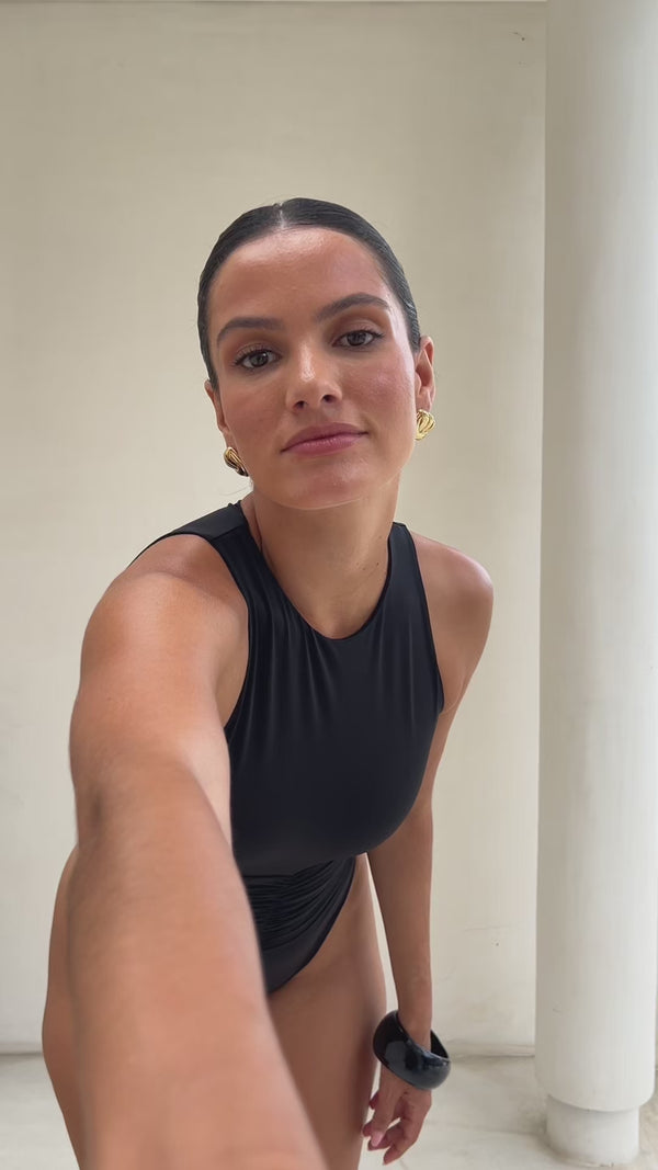 Model wearing Riot  one piece swimsuit with ruched waist in black.