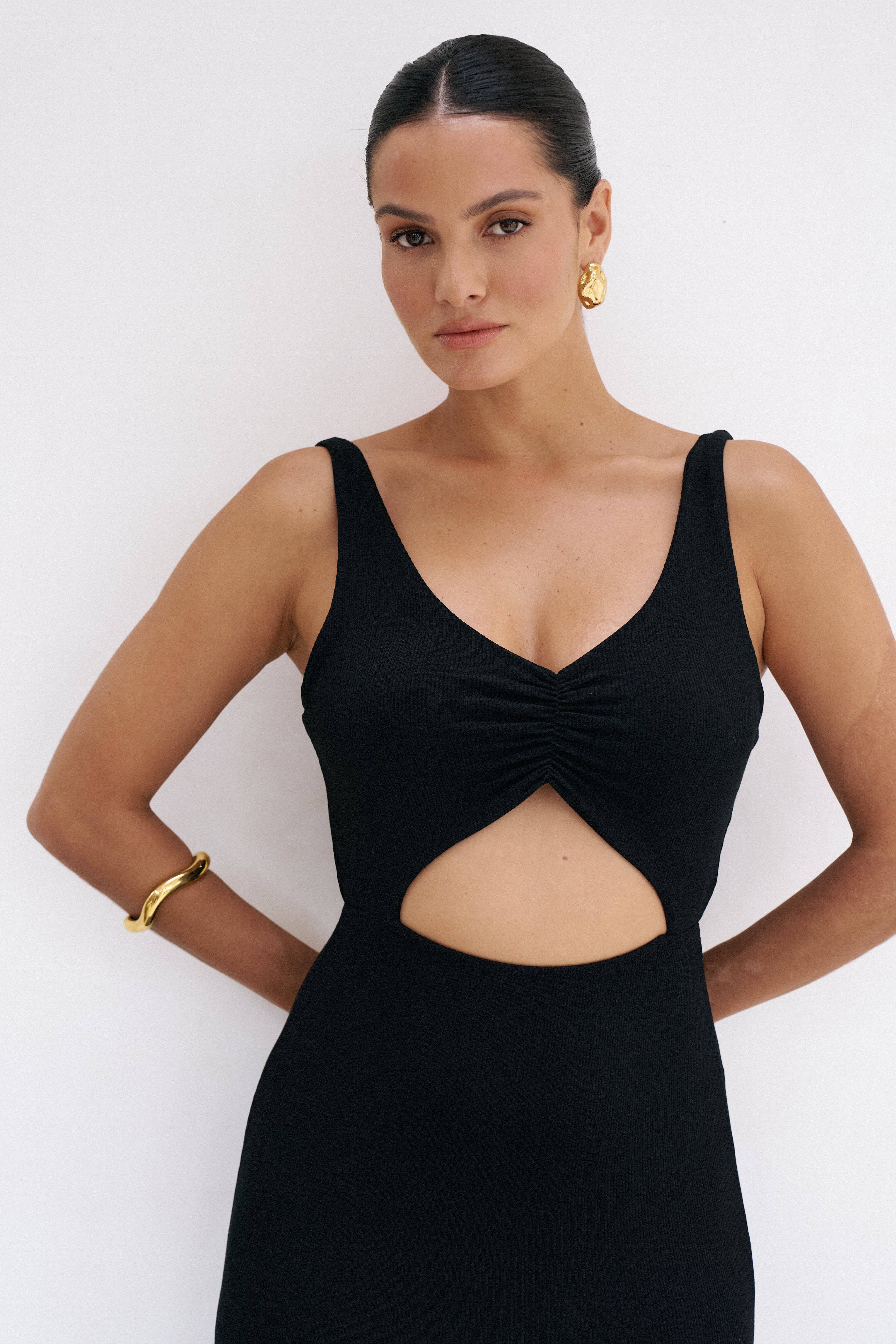 Woman wearing a riot swim black reily maxi dress with cut-out design against a white background
