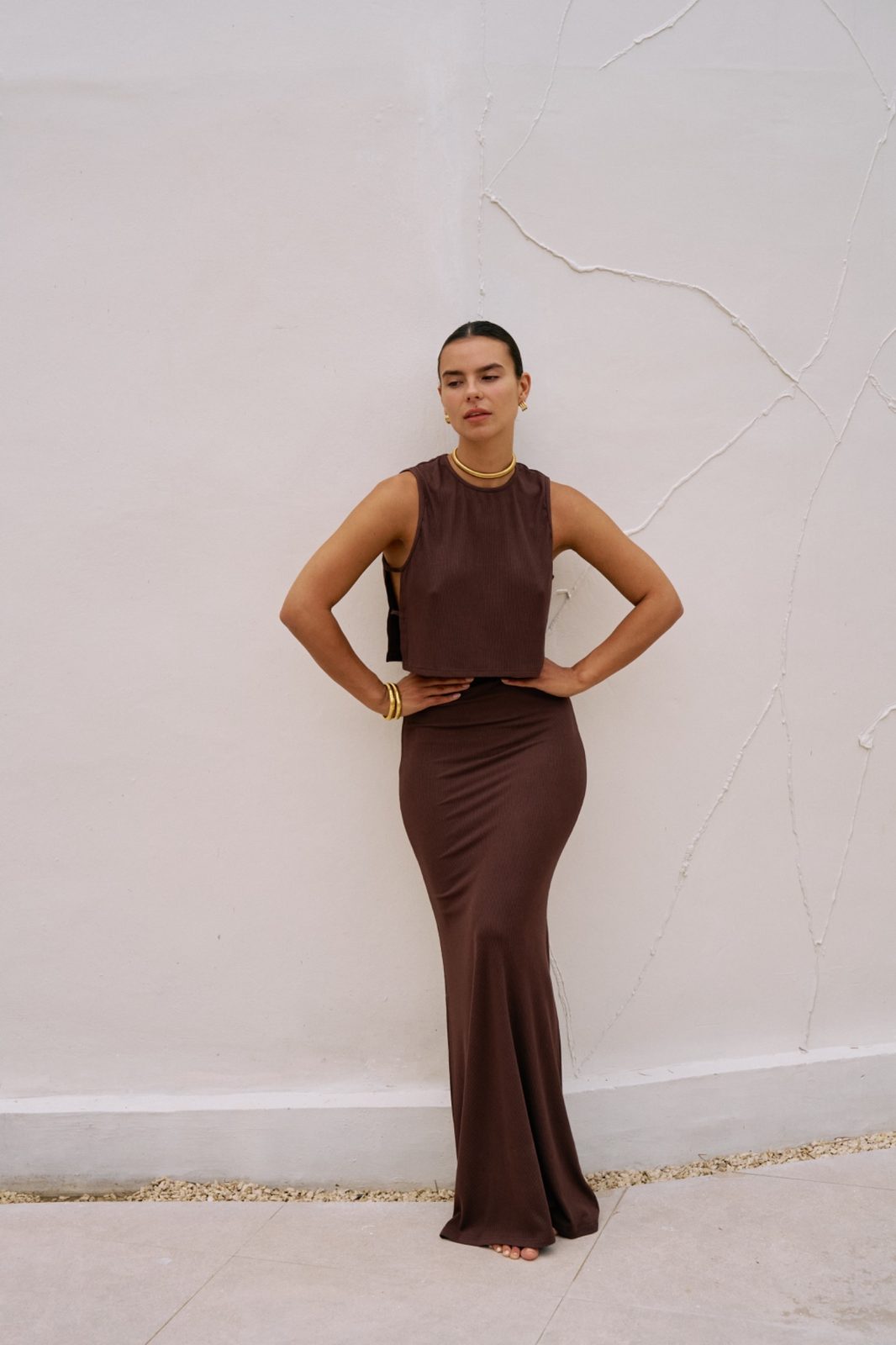 Full length view of woman in the chocolate brown Simi crop top and Dom ribbed maxi skirt set.
