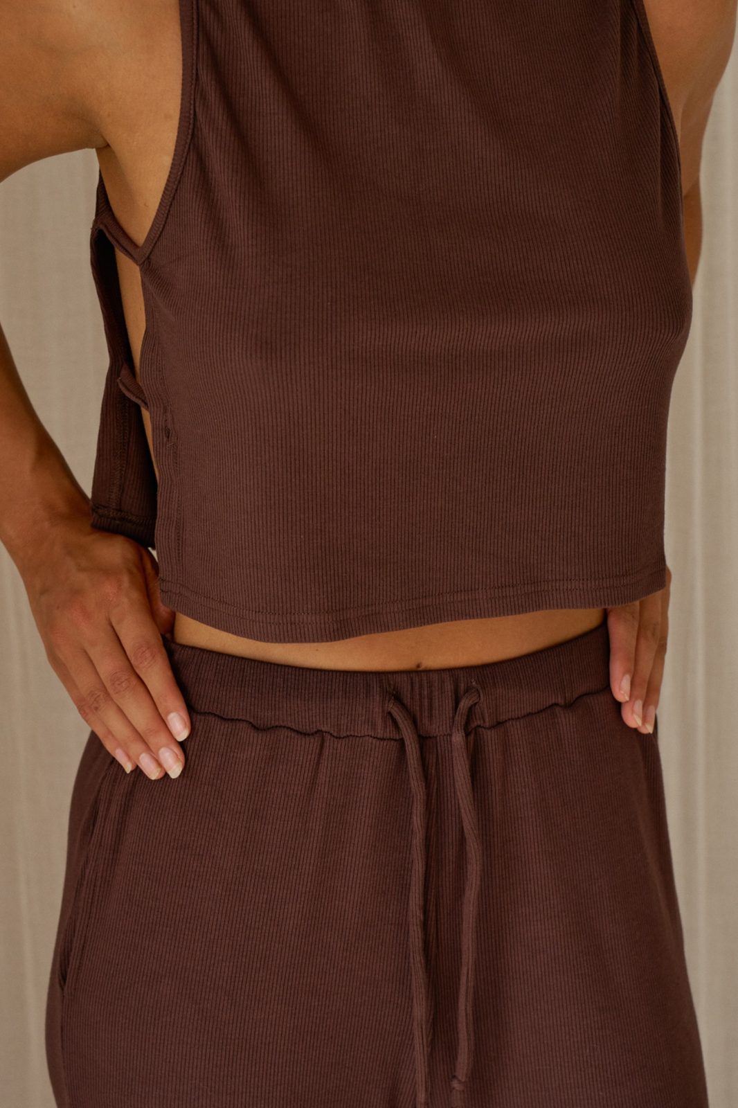 Close-up of woman lounging in the chocolate brown Simi top and Rory pant matching set.